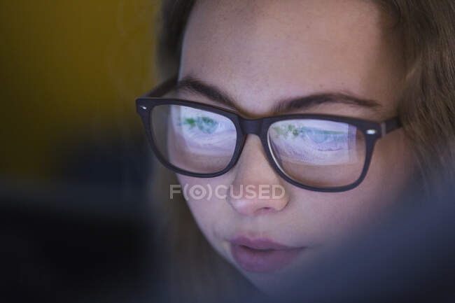 Close up focused teenage girl in eyeglasses looking at device screen — Stock Photo