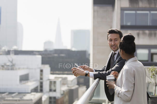 Les gens d'affaires parlent sur un balcon ensoleillé et urbain — Photo de stock