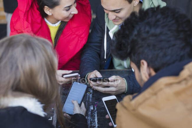 Молодые взрослые друзья используют смартфоны за столом кафе — стоковое фото