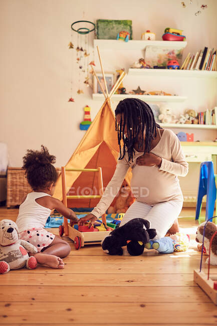 Madre incinta e figlia bambino che gioca con i giocattoli — Foto stock