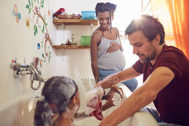 Embarazadas padres dando hija baño - foto de stock
