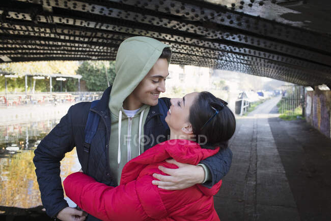 Glückliches, liebevolles junges Paar, das sich unter städtischer Brücke umarmt — Stockfoto