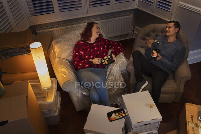 Couple taking a break from moving, eating sushi — Stock Photo