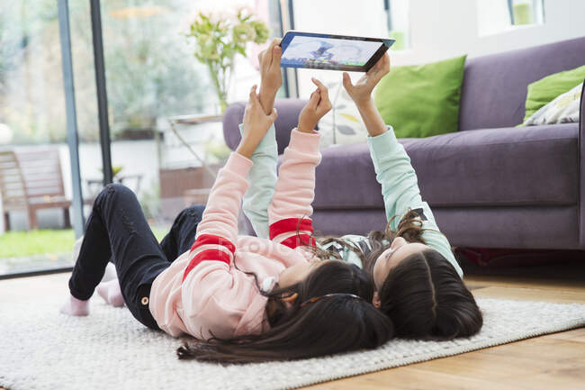 Meninas tomando selfie com tablet digital no chão da sala de estar — Fotografia de Stock