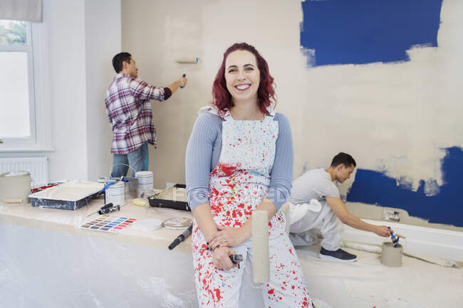 Retrato mujer confiada en overoles sala de pintura con amigos - foto de stock