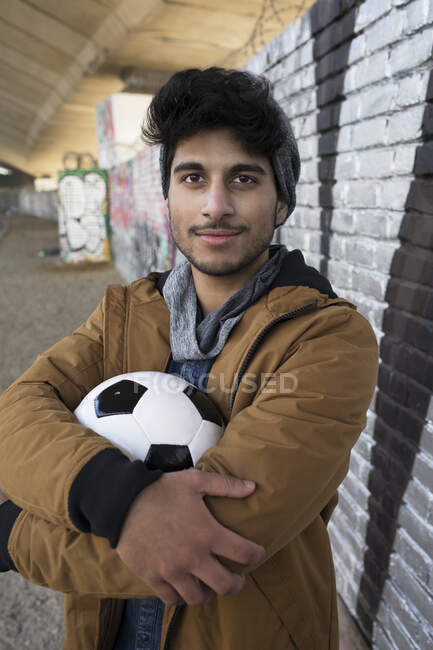 Ritratto giovane sicuro di sé con pallone da calcio in galleria urbana — Foto stock