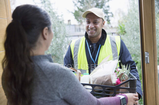 Woman greeting food deliveryman at front door — Stock Photo
