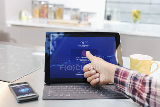 Mann loggt sich mit Fingerabdruck in Küche in digitales Tablet ein — Stockfoto