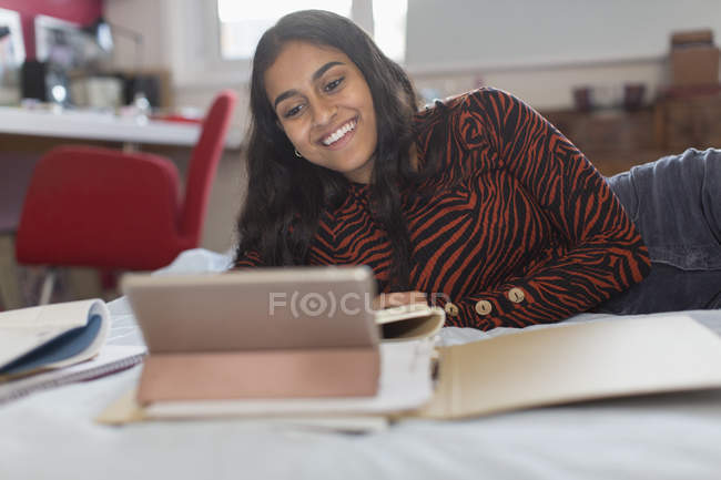 Lächelndes Teenager-Mädchen im Videochat mit digitalem Tablet auf dem Bett — Stockfoto