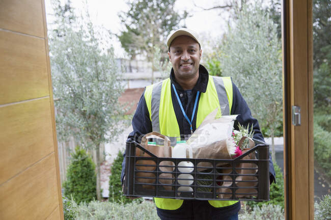 Portrait confident, friendly grocery deliveryman at front door — Stock Photo