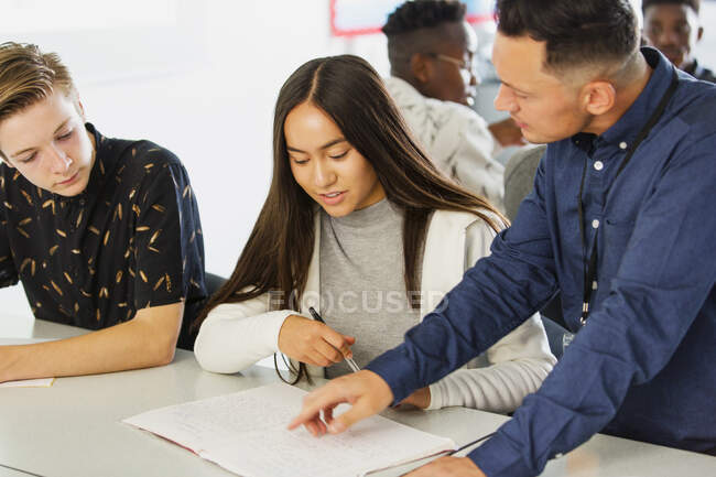 High school teacher helping students with homework in classroom — Stock Photo