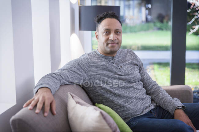 Портрет уверенный человек на диване гостиной — стоковое фото