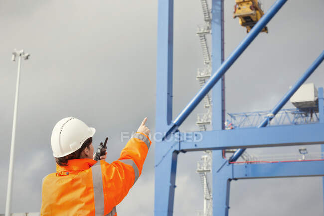 Dock worker avec talkie-walkie direction grue au chantier naval — Photo de stock
