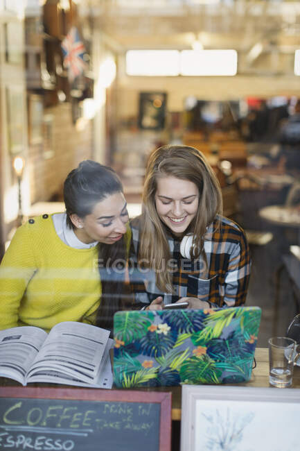 Sonriendo jóvenes estudiantes universitarias que estudian en la cafetería - foto de stock