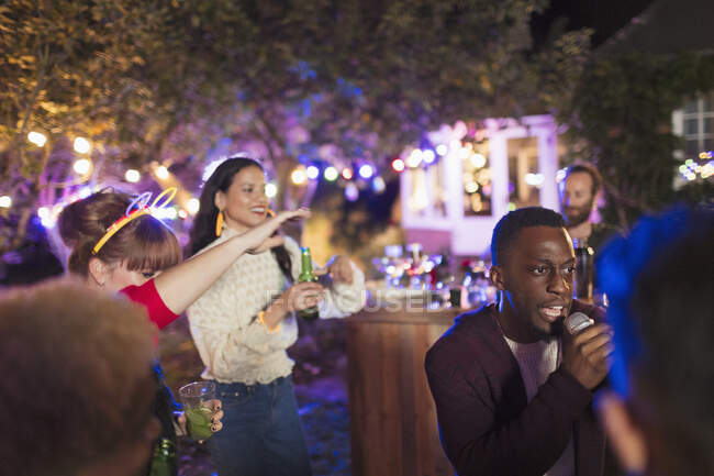 Amici che bevono e cantano karaoke alla festa — Foto stock