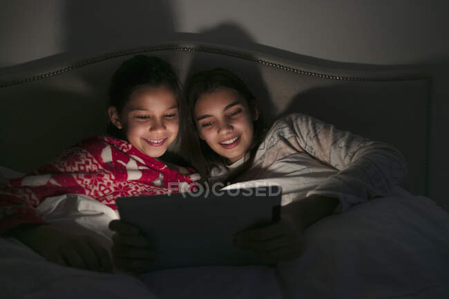 Девочки смотрят кино на цифровом планшете в темной спальне — стоковое фото