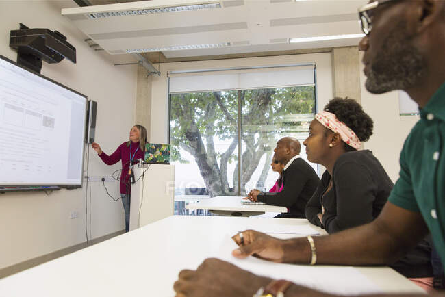 Estudantes universitários comunitários assistindo instrutor lição de liderança na tela de projeção em sala de aula — Fotografia de Stock