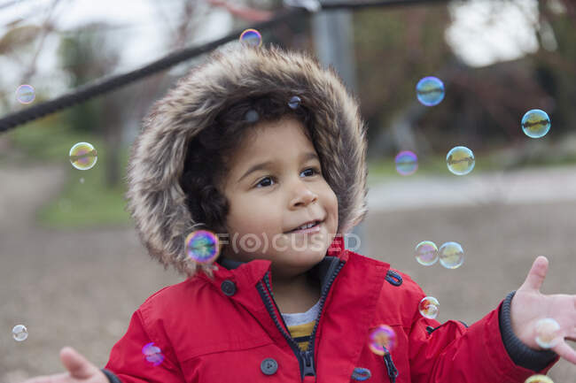 Грайливий маленький хлопчик грає з бульбашками — стокове фото