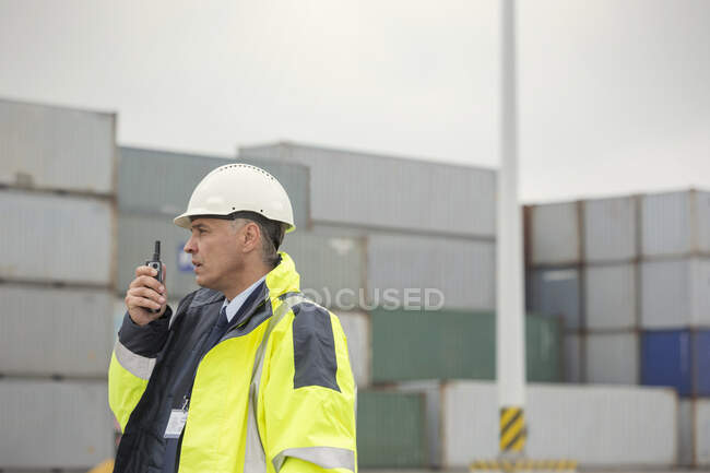 Dock manager with walkie-talkie among cargo containers at shipyard — Stock Photo