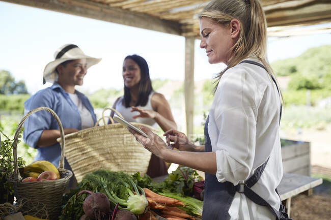 Женщина с цифровыми планшетами работает на фермерском рынке — стоковое фото