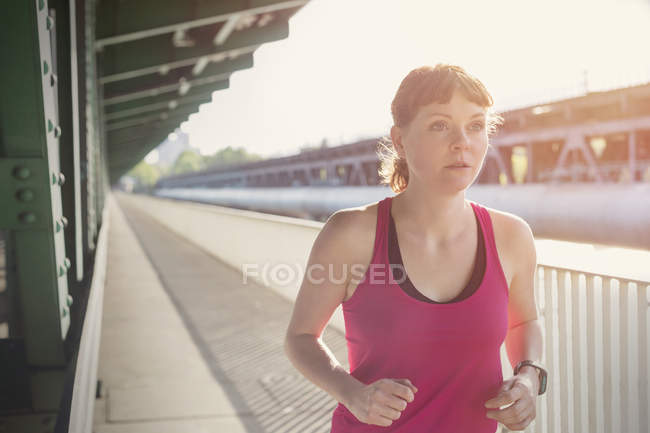 Mujer joven y decidida corriendo por la soleada estación de tren - foto de stock