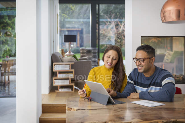Couple paying bills at digital tablet at dining table — Stock Photo