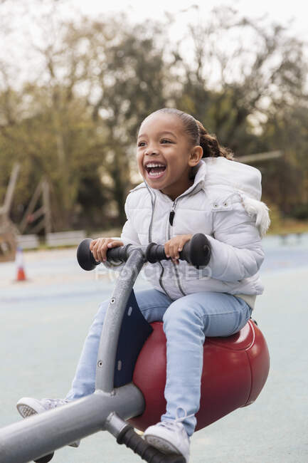 Playful, happy girl playing on playground seesaw — Stock Photo
