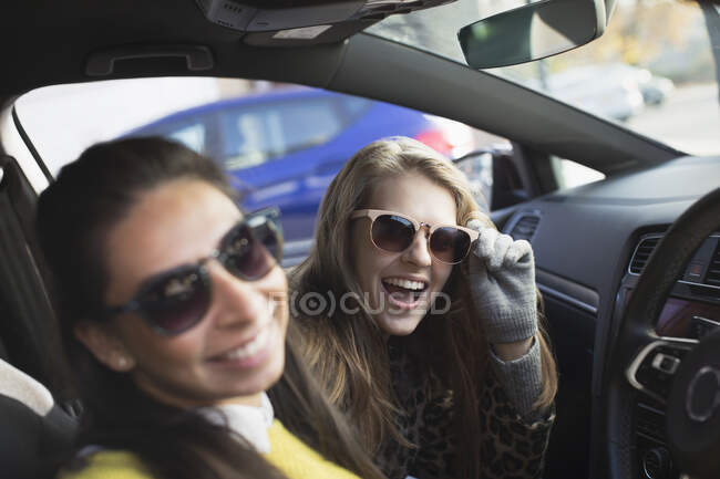 Retrato feliz, brincalhão jovens mulheres vestindo óculos de sol no carro — Fotografia de Stock