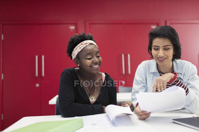 Female community college students discussing paperwork in classroom — Stock Photo