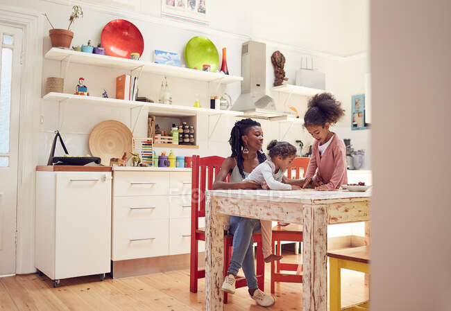 Mãe e filhas na mesa da cozinha — Fotografia de Stock