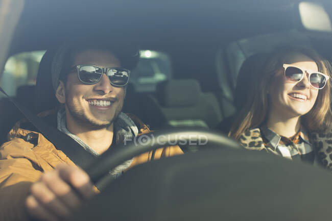 Счастливая молодая пара в солнечных очках в машине — стоковое фото