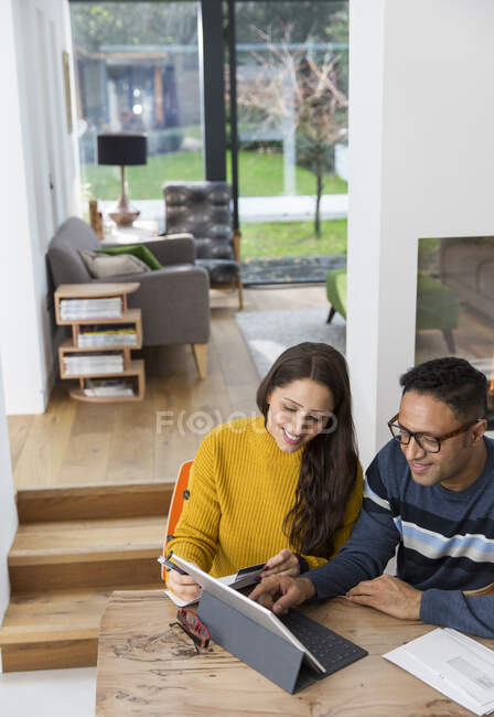 Couple paying bills at digital tablet at dining room table — Stock Photo