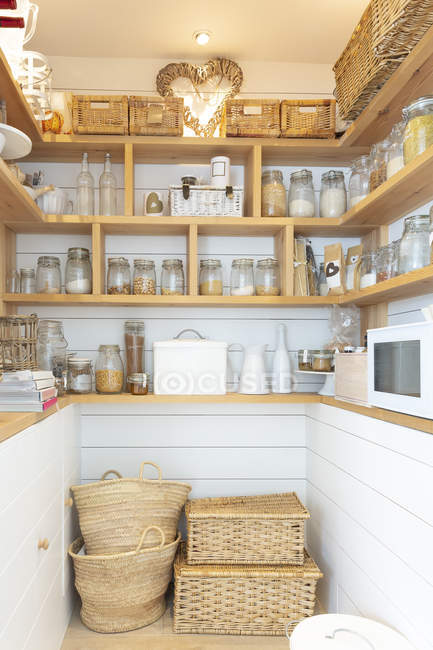 Woven baskets and food jars in pantry — Stock Photo
