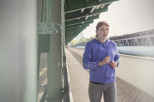 Dedicated young woman running along sunny train station platform — Stock Photo