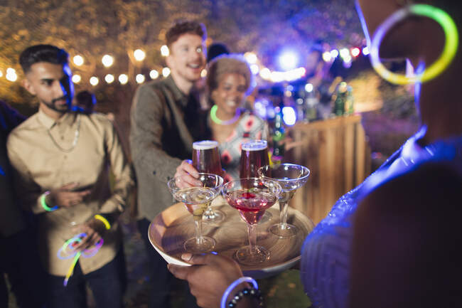 Женщина, подающая коктейли друзьям на вечеринке в саду — стоковое фото