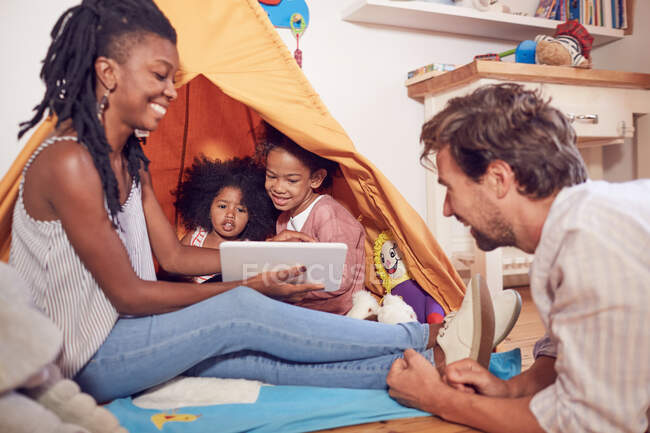 Young family using digital tablet on teepee — Stock Photo