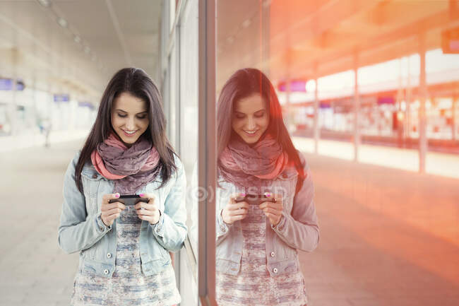 Junge Frau benutzt Smartphone im Bahnhof — Stockfoto