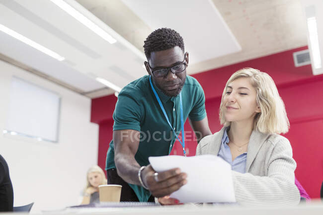 Community college instructor helping student with paperwork in classroom — Stock Photo