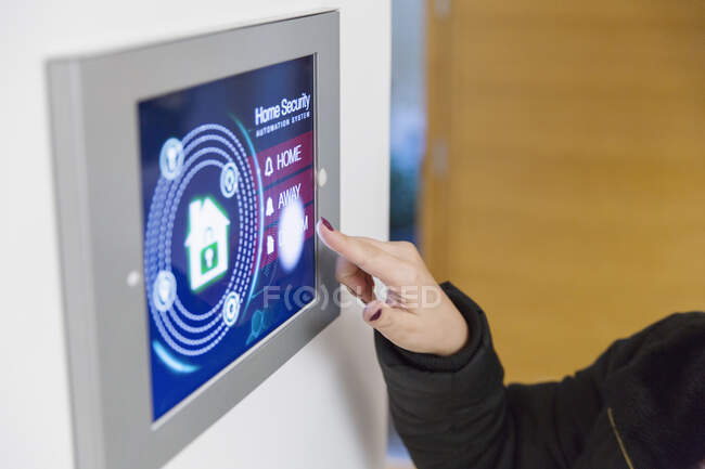 Woman setting smart home security alarm at touch screen — Stock Photo