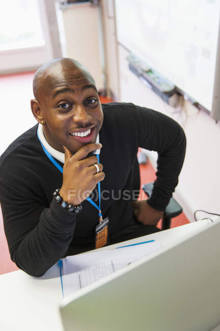 Уверенный в себе портрет, улыбающийся преподаватель колледжа за компьютером в классе — стоковое фото