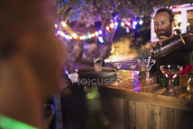 Cantinero vertiendo cócteles en la fiesta del jardín - foto de stock