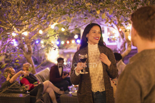 Друзья разговаривают и пьют вино на вечеринке в саду — стоковое фото
