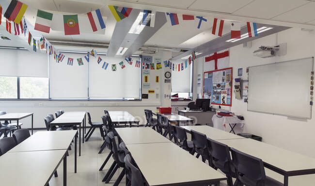National flags hanging above tables in classroom — Stock Photo