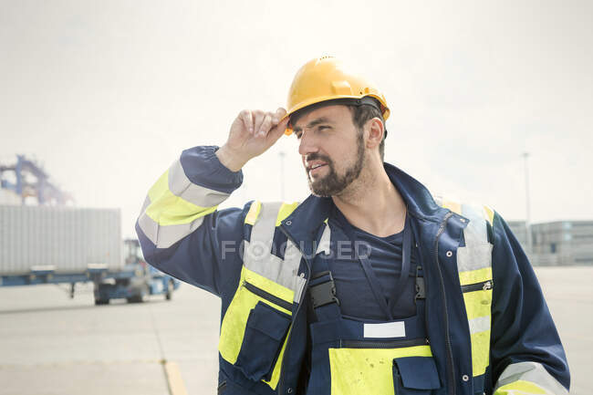 Trabajador portuario con casco en astillero soleado - foto de stock