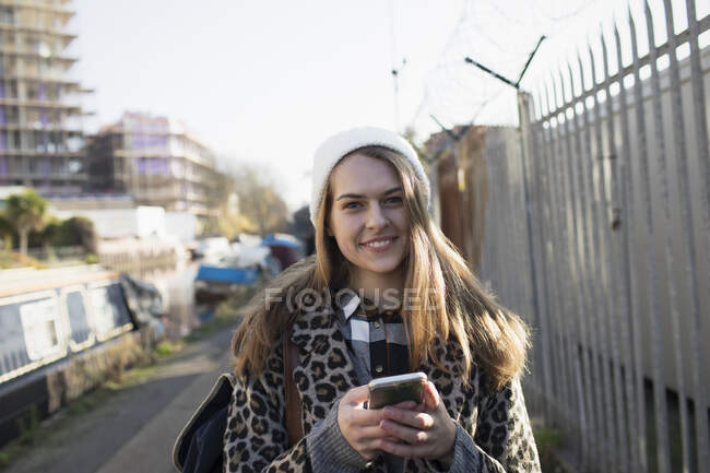 Портрет усміхається молодій жінці з розумним телефоном на міському тротуарі. — стокове фото