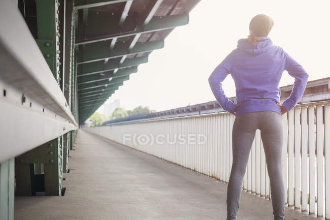 Молода жінка бігун відпочиває руками на стегнах на платформі вокзалу — стокове фото