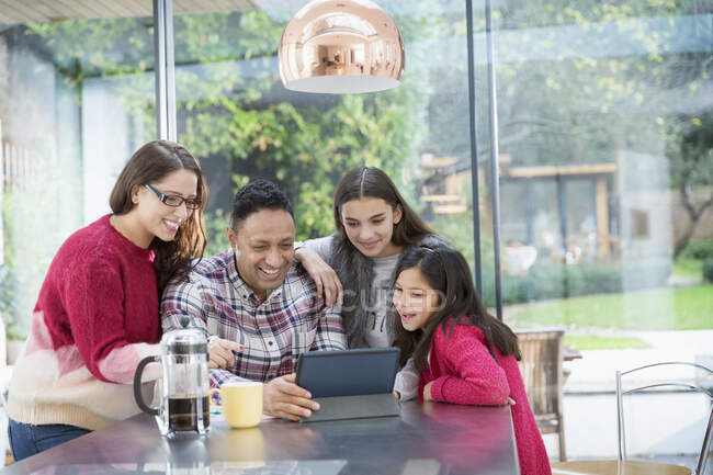 Família feliz usando tablet digital na mesa da cozinha — Fotografia de Stock