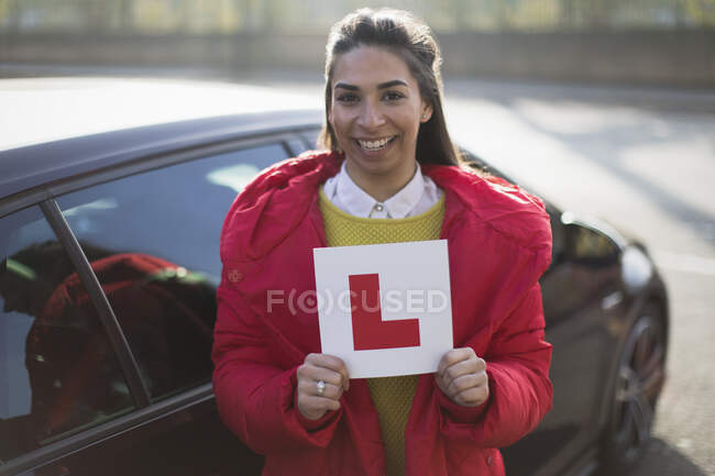 Portrait confident, happy young woman holding learners permit by car — Stock Photo