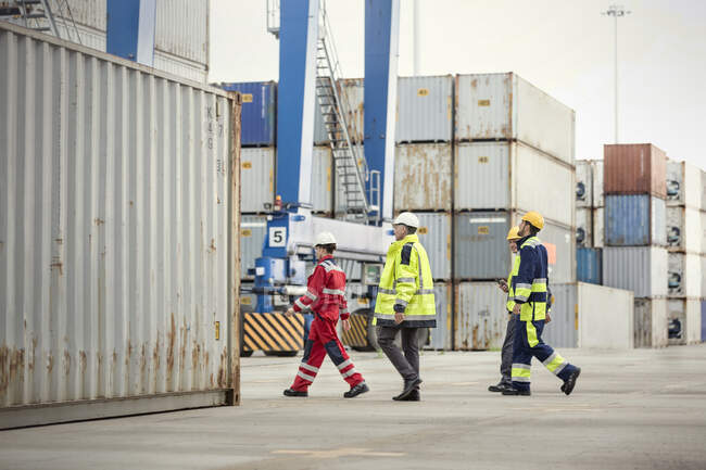 Lavoratori portuali che camminano lungo i container del cantiere navale — Foto stock