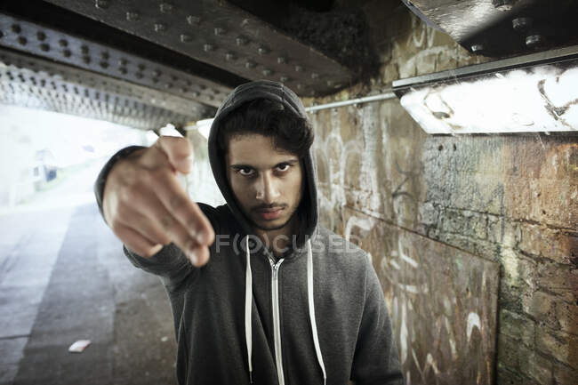 Portrait tough young man gesturing finger gun in urban tunnel — Stock Photo
